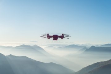 Drone flying over foggy and snowy high hills and mountains